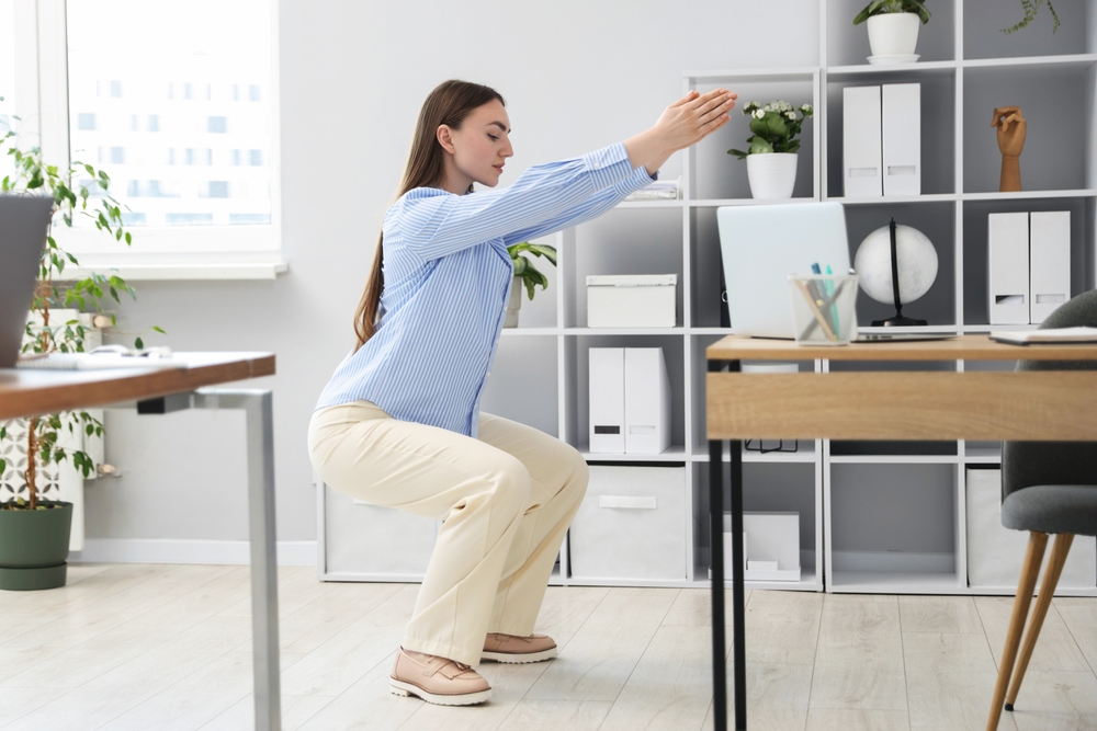 nő guggolást végez az irodában